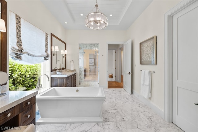 bathroom with a raised ceiling, a bathtub, vanity, and an inviting chandelier