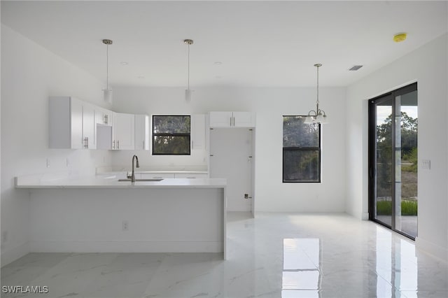 735 Goldrock Rd, Lehigh Acres, FL 33974 - kitchen with a sink, a peninsula, white cabinets, light marble finish flooring, and light countertops