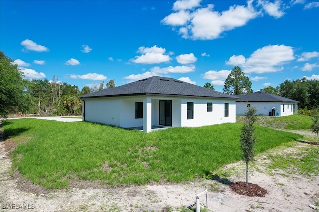 735 Goldrock Rd, Lehigh Acres, FL 33974 - back of property with a lawn, stucco siding, and roof with shingles