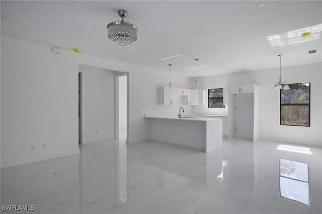 735 Goldrock Rd, Lehigh Acres, FL 33974 - kitchen with a peninsula, white cabinetry, light marble finish floors, a sink, and light countertops