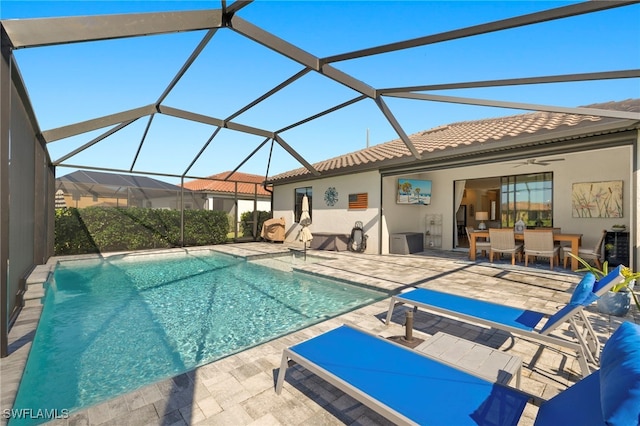 view of swimming pool featuring glass enclosure, a patio area, and ceiling fan