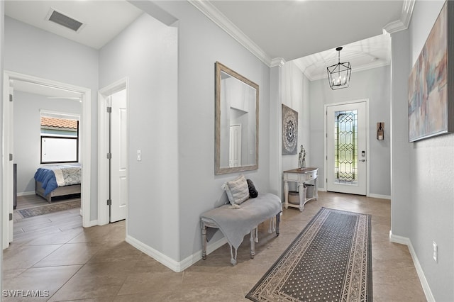 tiled foyer entrance with a healthy amount of sunlight, a notable chandelier, and crown molding