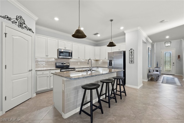 kitchen with appliances with stainless steel finishes, an island with sink, white cabinets, and sink