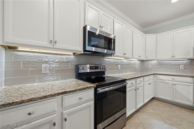 kitchen with appliances with stainless steel finishes, ornamental molding, white cabinets, and light stone counters