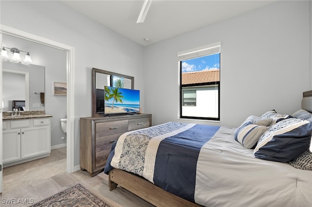 bedroom with ceiling fan, sink, and connected bathroom