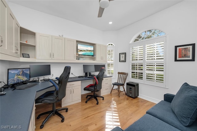 office area with built in desk, ceiling fan, and light hardwood / wood-style flooring