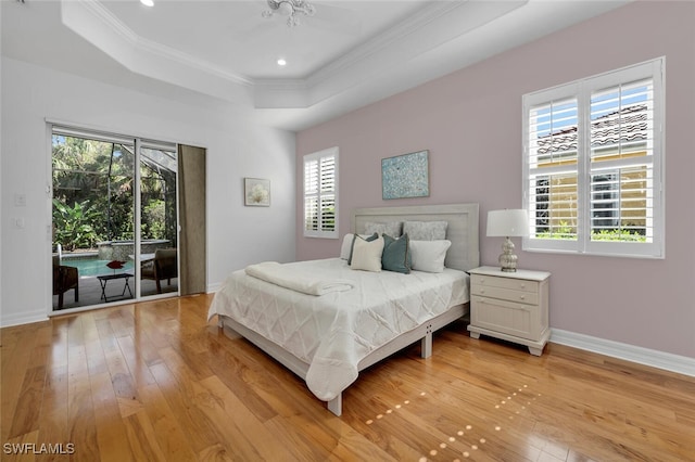 bedroom with crown molding, access to exterior, a raised ceiling, and light hardwood / wood-style flooring