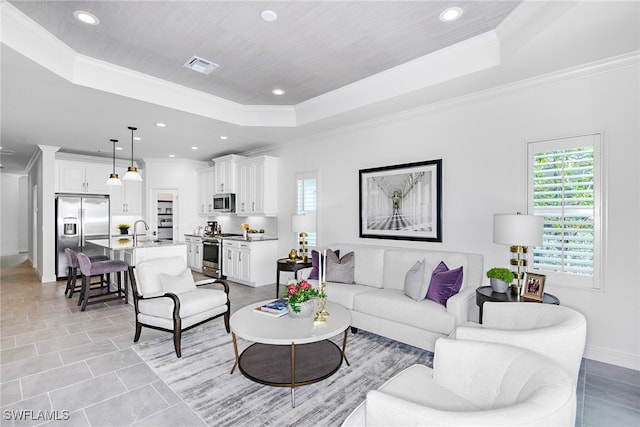 living room featuring sink, crown molding, and a tray ceiling