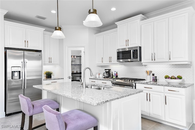 kitchen featuring light stone counters, white cabinetry, appliances with stainless steel finishes, decorative light fixtures, and sink