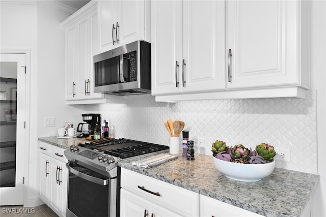 kitchen featuring stainless steel appliances, light stone countertops, white cabinets, and tasteful backsplash