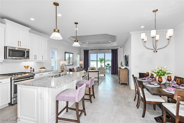 kitchen featuring light stone counters, white cabinetry, decorative light fixtures, and appliances with stainless steel finishes