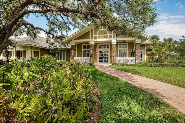 craftsman house with a front yard, french doors, and a porch