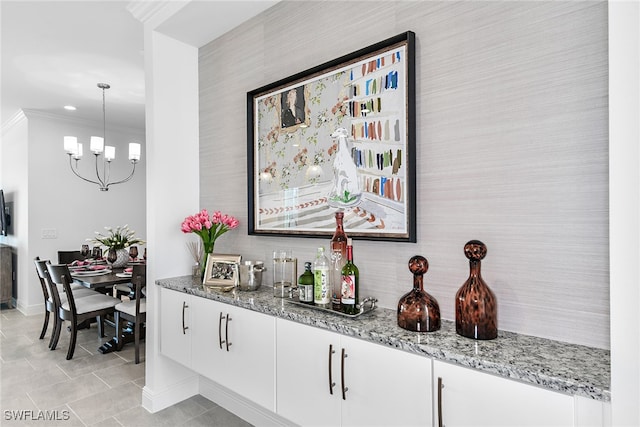 interior space featuring white cabinetry, crown molding, decorative light fixtures, and stone countertops