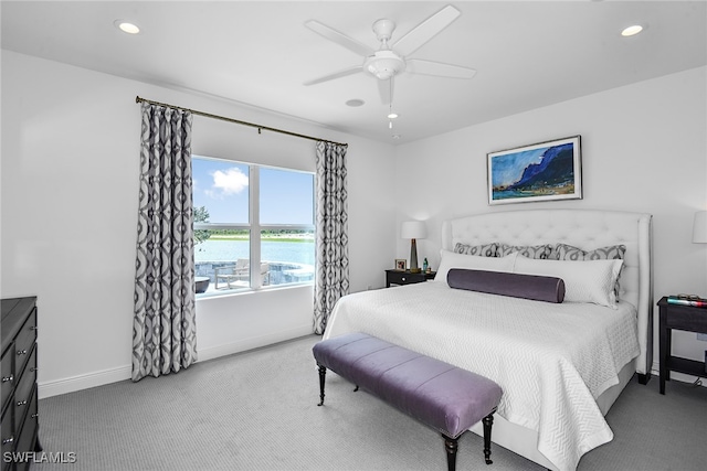 carpeted bedroom with a water view and ceiling fan