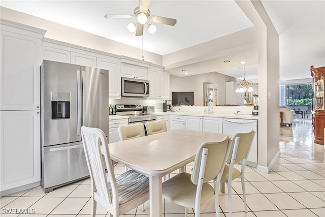 dining room with ceiling fan with notable chandelier, light tile patterned floors, and sink