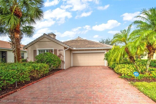 view of front of property with stucco siding, a chimney, decorative driveway, and a garage