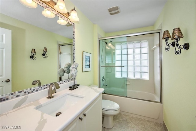 bathroom featuring toilet, vanity, bath / shower combo with glass door, and tile patterned flooring