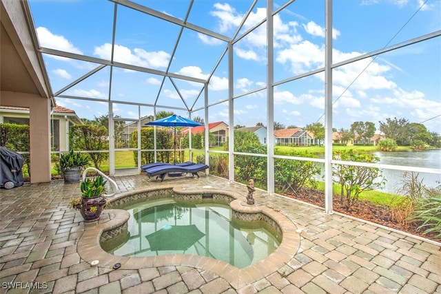 view of pool with a jacuzzi, glass enclosure, a water view, and a patio area