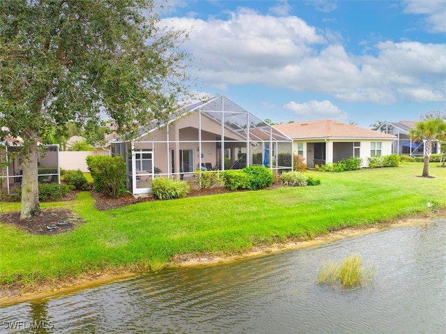 back of property with a lanai, a water view, and a yard