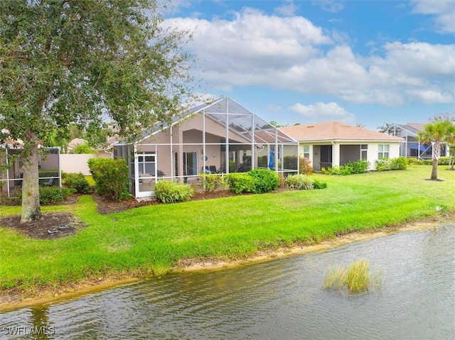 rear view of property featuring stucco siding, a water view, a lawn, and a lanai