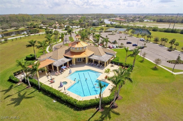 view of swimming pool with a lawn, a water view, and a patio area