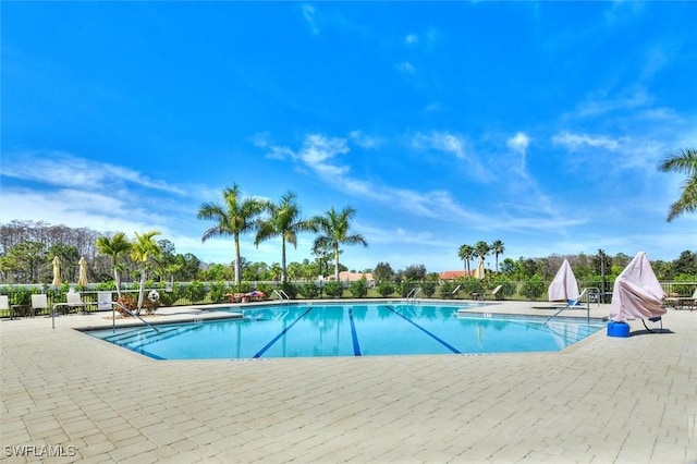 community pool with a patio area and fence