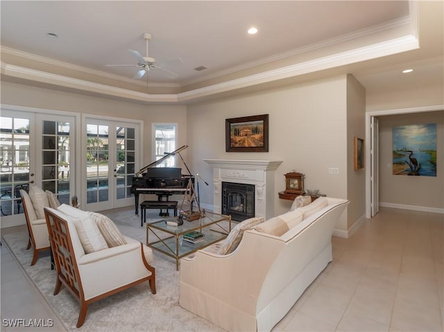 living room featuring ceiling fan, ornamental molding, a tray ceiling, and french doors