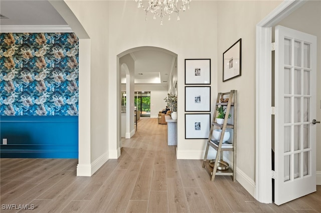 hall with a chandelier, light hardwood / wood-style flooring, and crown molding