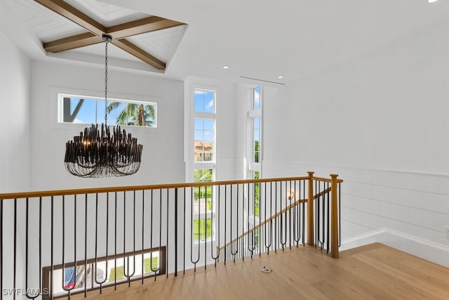 corridor featuring hardwood / wood-style flooring, plenty of natural light, an inviting chandelier, and beam ceiling