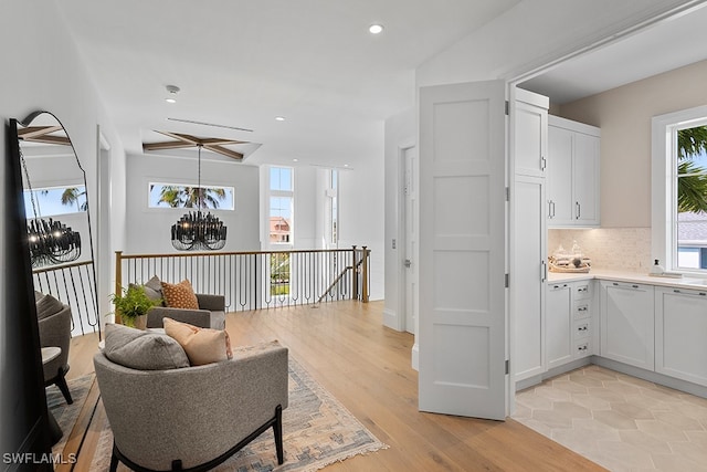 kitchen featuring white cabinetry, a chandelier, decorative backsplash, and light wood-type flooring