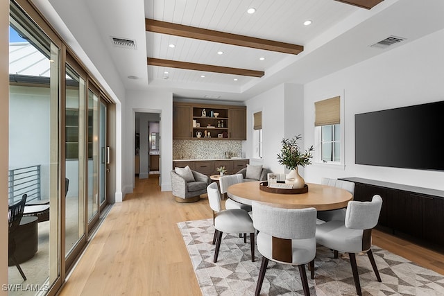 dining area with light hardwood / wood-style flooring, beamed ceiling, wooden ceiling, and plenty of natural light