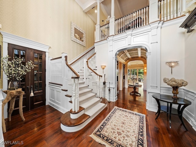 foyer with dark wood-type flooring, high vaulted ceiling, and french doors