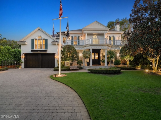 view of front of home with a garage, a balcony, and a yard