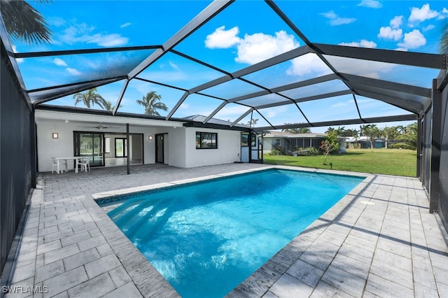 view of swimming pool with a patio, glass enclosure, a lawn, and ceiling fan