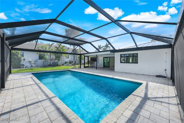 view of swimming pool featuring a patio area, a lawn, and a lanai