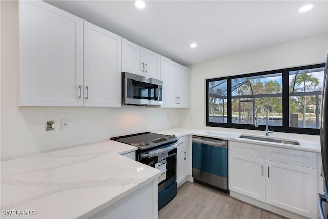 kitchen featuring white cabinets, sink, light stone counters, and stainless steel appliances