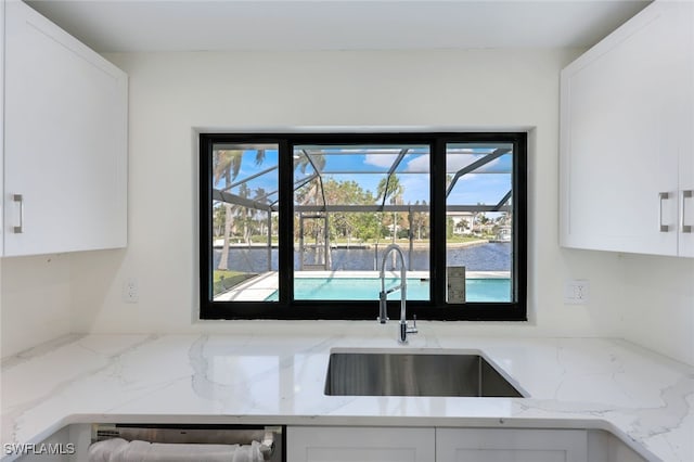 kitchen featuring white cabinetry, sink, and light stone countertops