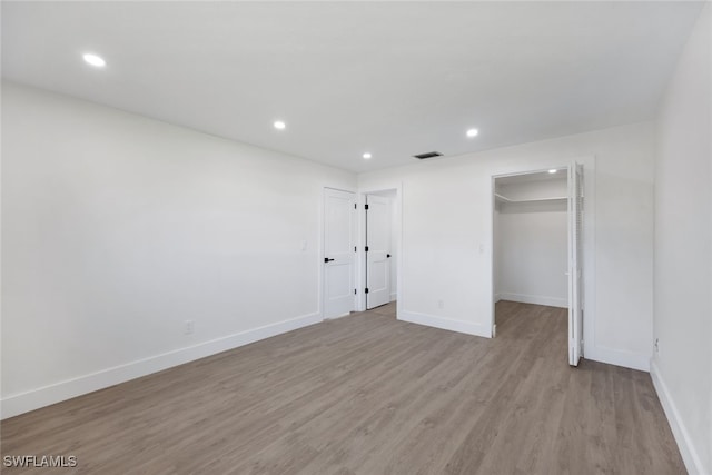 unfurnished bedroom with light wood-type flooring, a walk in closet, and a closet