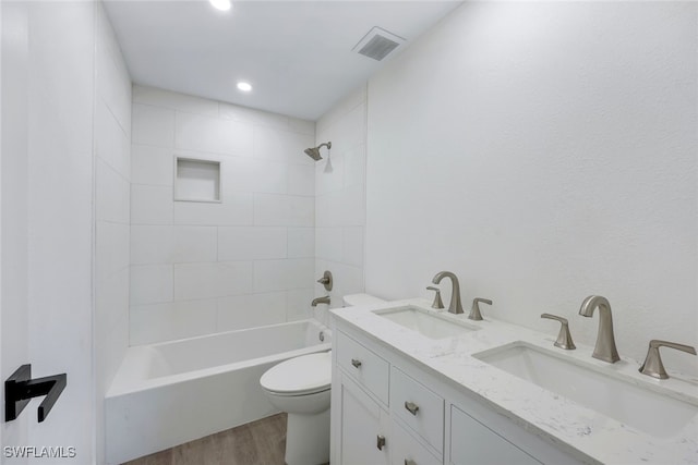 full bathroom featuring toilet, vanity, hardwood / wood-style floors, and tiled shower / bath