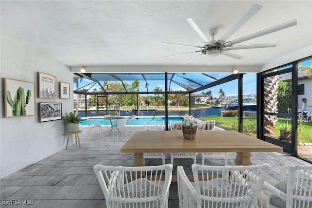 view of patio with a lanai, a water view, and ceiling fan