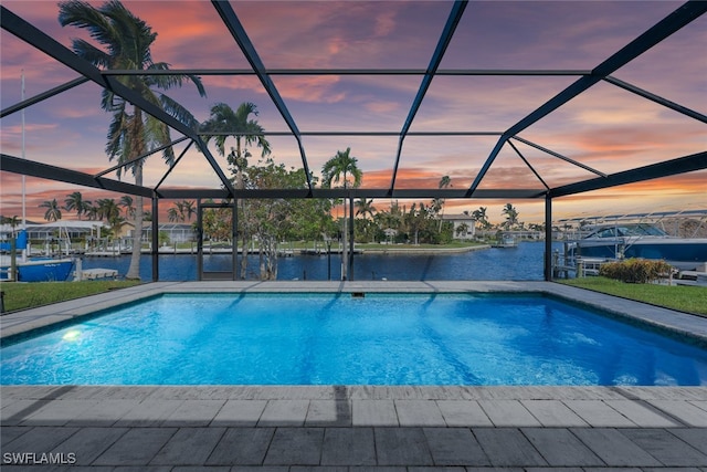 pool at dusk featuring glass enclosure and a water view