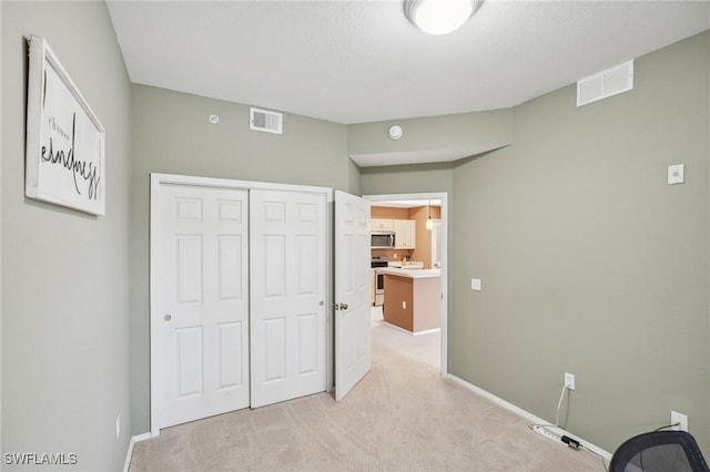 unfurnished bedroom featuring light colored carpet, a closet, visible vents, and baseboards