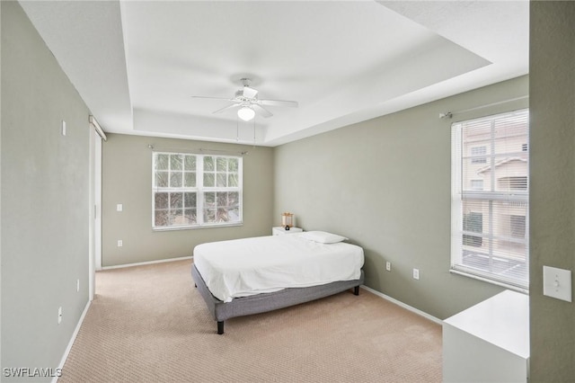 bedroom with baseboards, a tray ceiling, ceiling fan, and light colored carpet