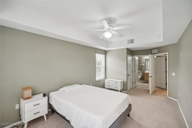 bedroom featuring light colored carpet, a raised ceiling, visible vents, and baseboards