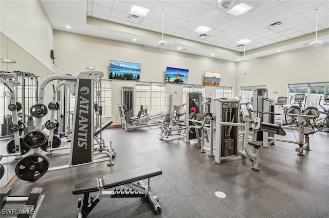 gym with a high ceiling, a drop ceiling, and visible vents