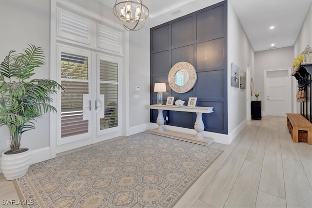 entryway with light hardwood / wood-style flooring and an inviting chandelier