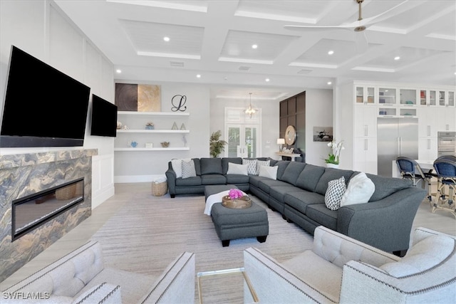 carpeted living room with ceiling fan with notable chandelier, beam ceiling, a fireplace, and coffered ceiling