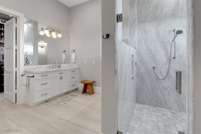 bathroom with a tile shower, vanity, and tile patterned floors