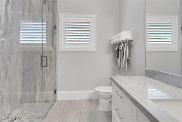 bathroom with hardwood / wood-style flooring, vanity, toilet, and a shower with shower door