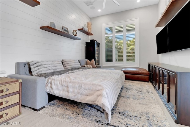 bedroom featuring ceiling fan and wooden walls